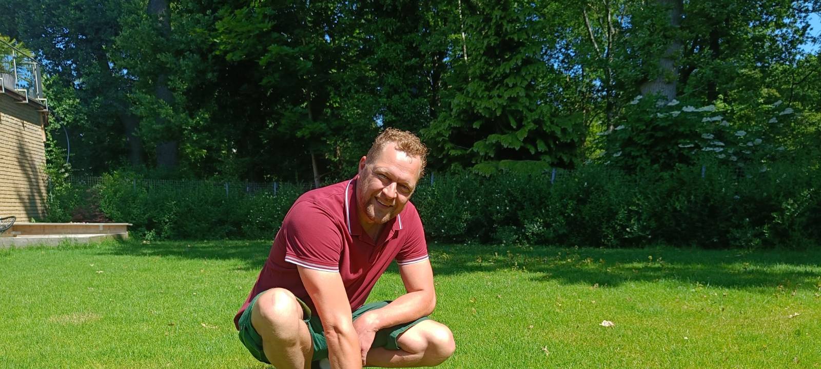 Gartenbauer Matthias Pölling zeigt auf dem Rasen im Garten