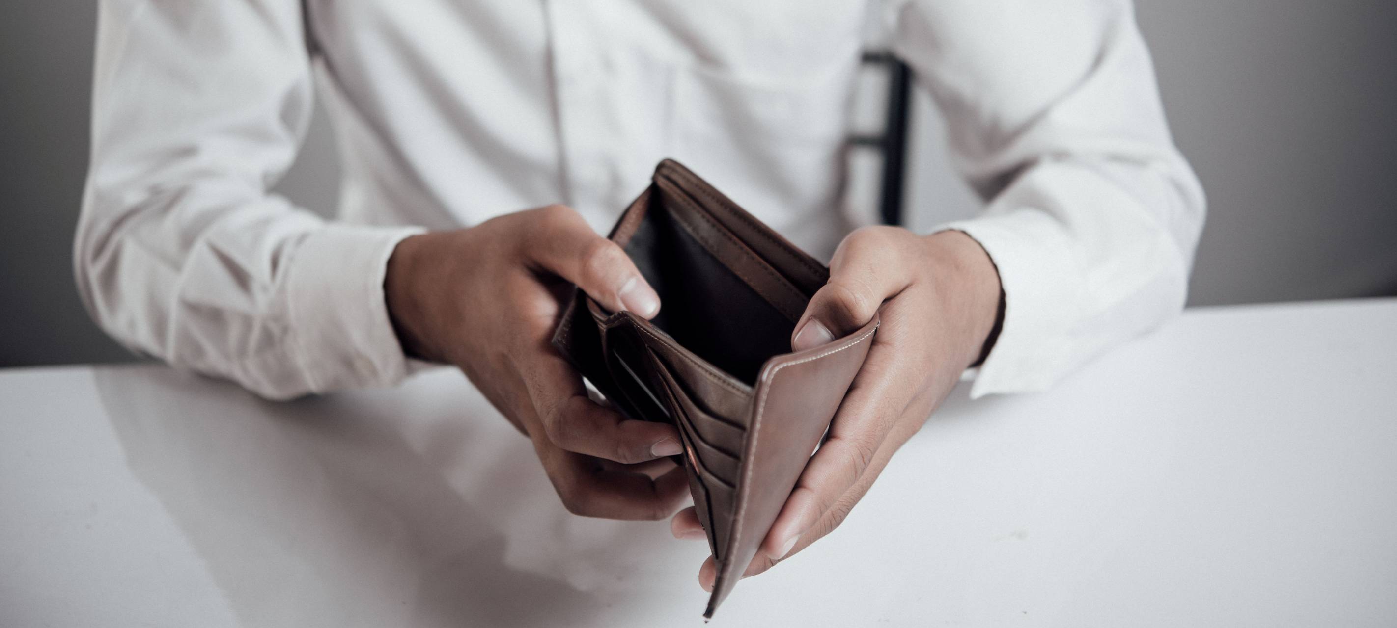 Ein Mann der ein leeres Portmonee in der Hand hält