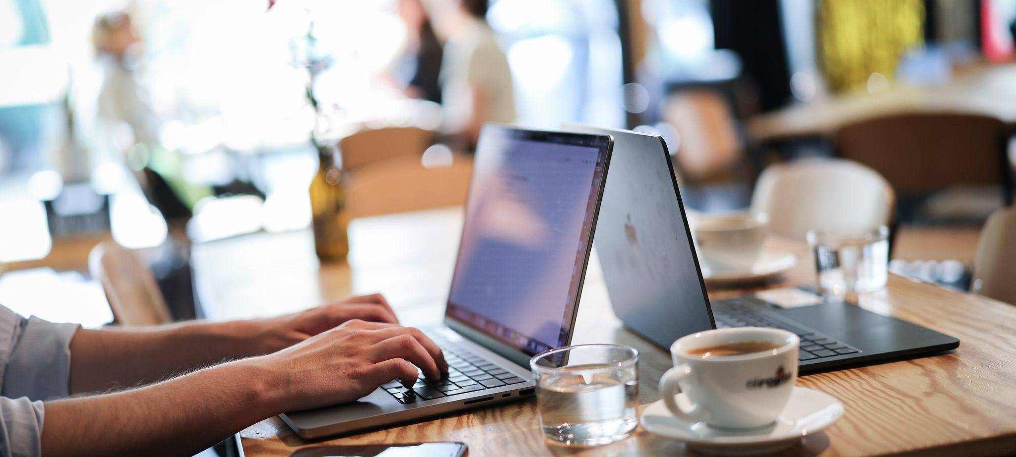 Ein Mensch arbeitet an seinem Computer in einem Café