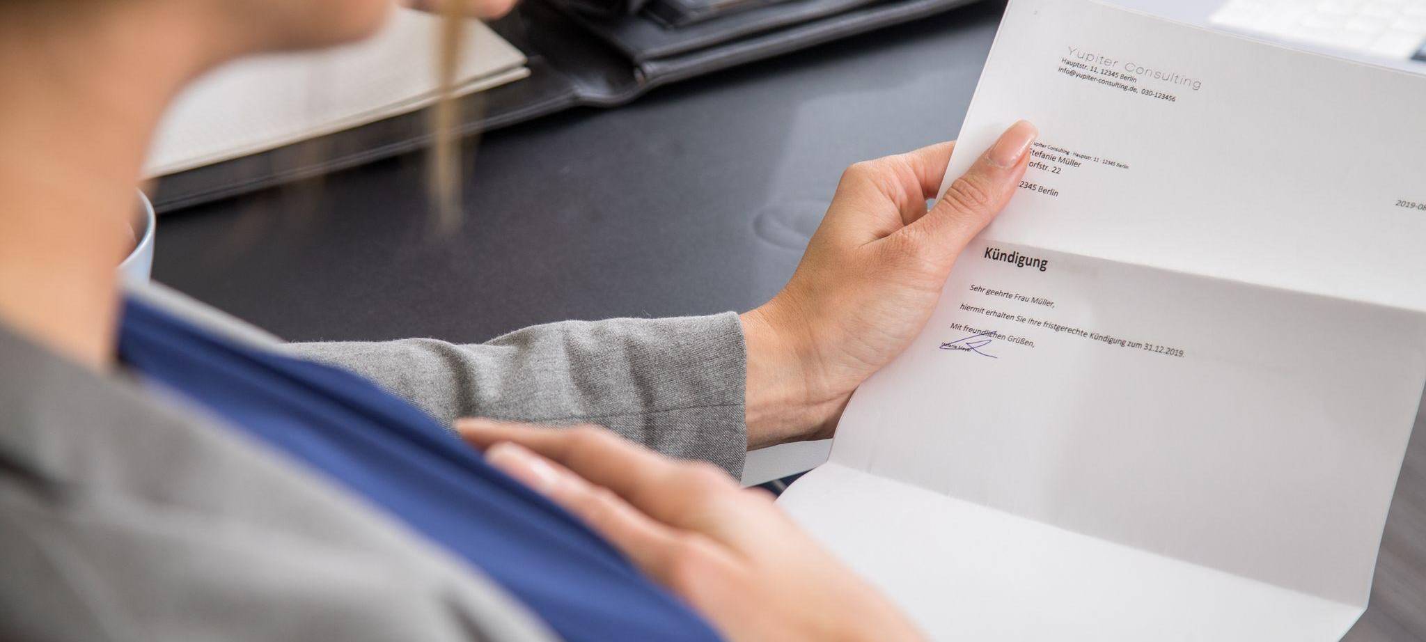 Eine schwangere Frau hält eine Kündigung in der Hand